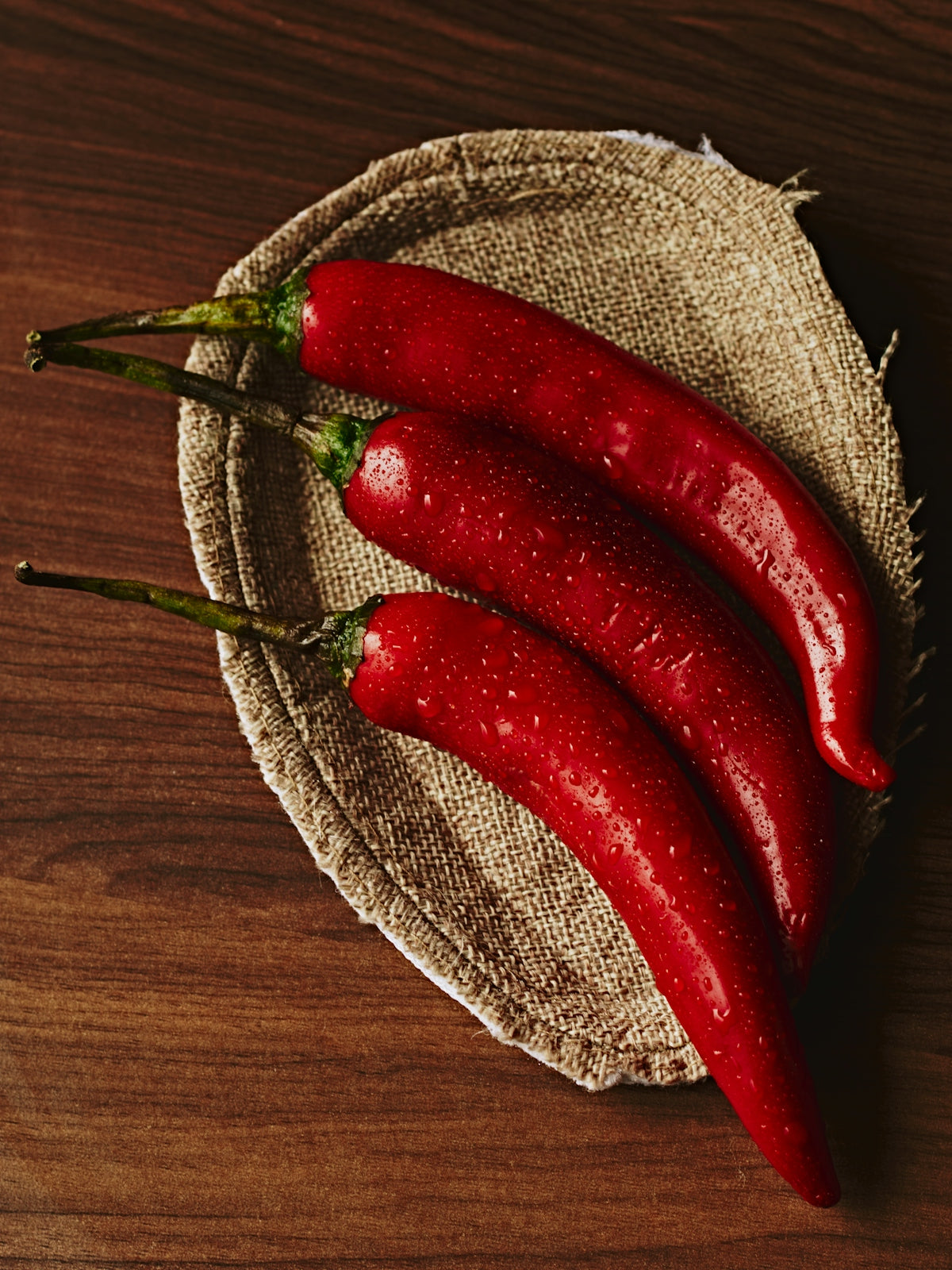 Three red chili peppers on a textured surface.