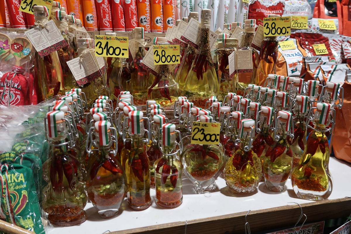 Chili-infused oil bottles displayed for sale at a market stall.